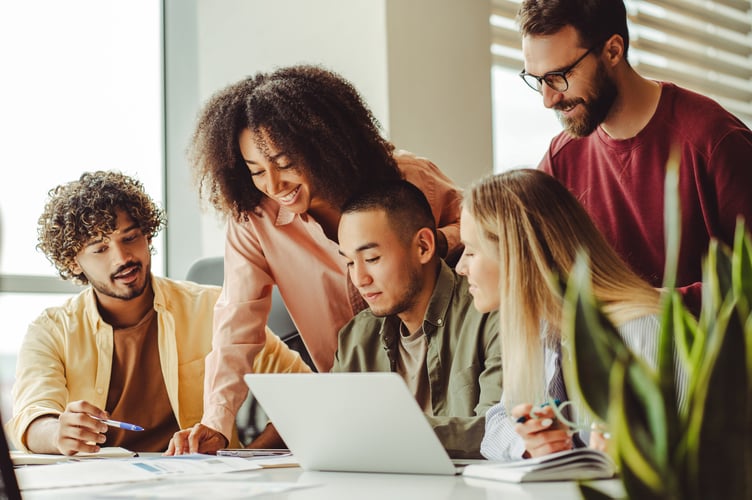 Group of smiling multiracial university students using laptop exam preparation studying together. Education concept. Young team, colleagues meeting, working, planning startup project in modern office 